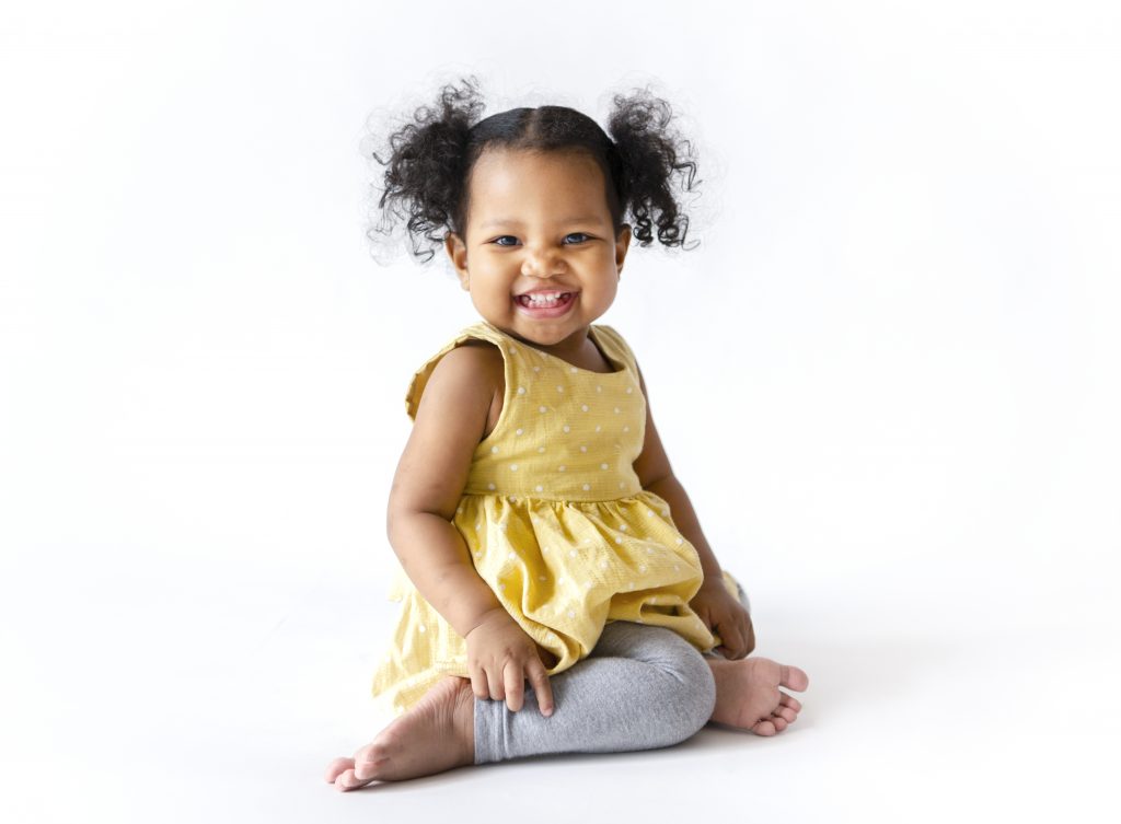 Happy little girl in a yellow dress sitting