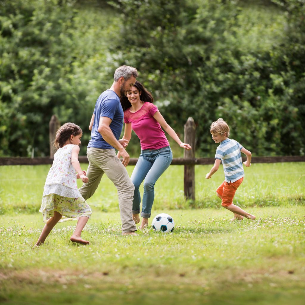 Cheerful family playing football in a garden